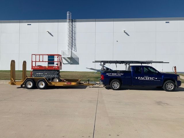 A truck with a trailer attached to it is parked in front of a building.