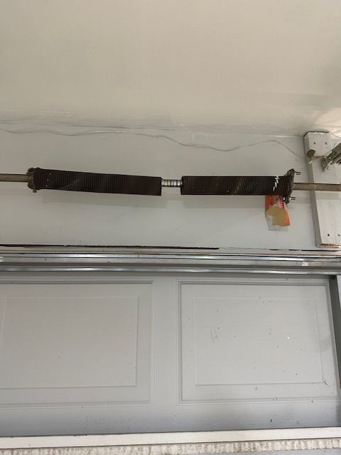 A garage door spring is hanging from the ceiling of a garage.