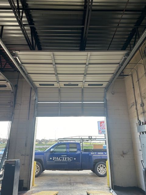 A blue truck is parked in a garage with the door open.