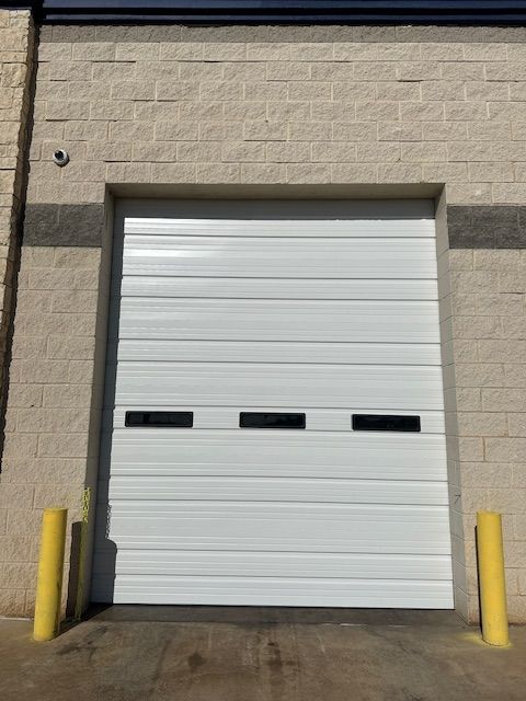 A white garage door is open on a brick building