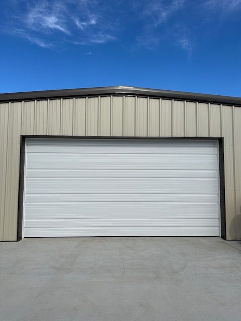 A garage with a white garage door and a blue sky in the background.
