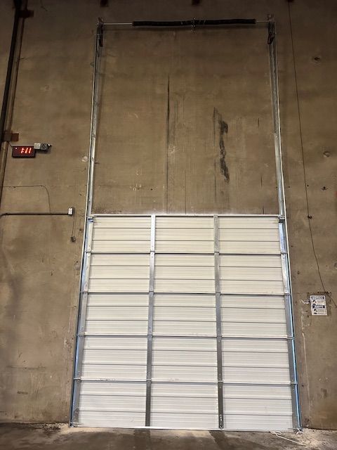 A large white garage door is open in a warehouse.