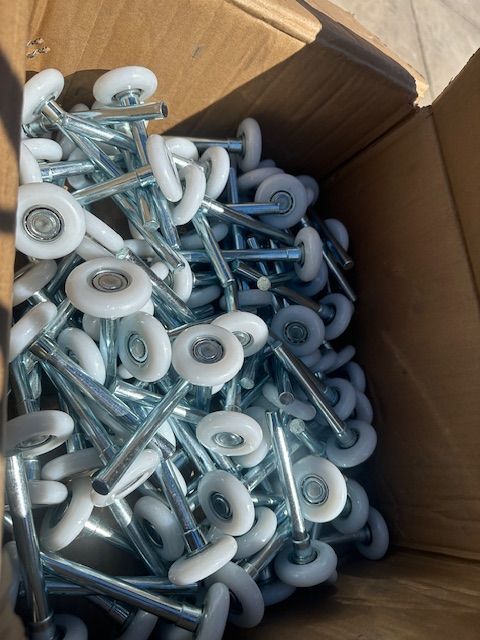 A box filled with lots of white wheels and screws