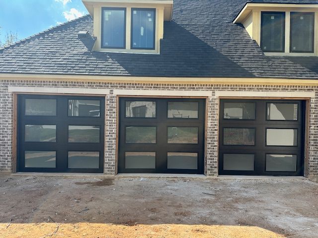 A house with three garage doors and a brick building.