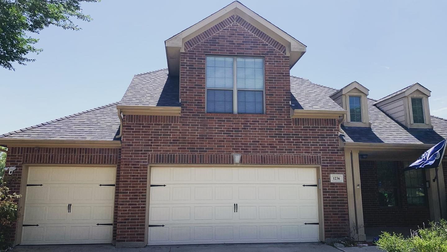 A large brick house with two white garage doors