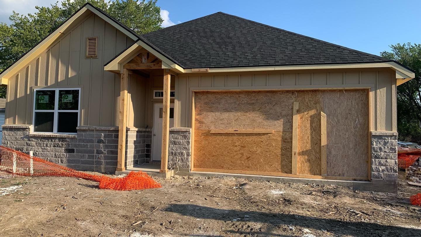 A house that is being built with a garage and a porch.