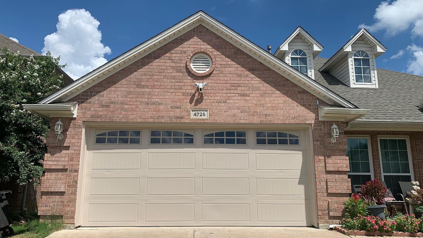 A brick house with a white garage door and a gray roof.