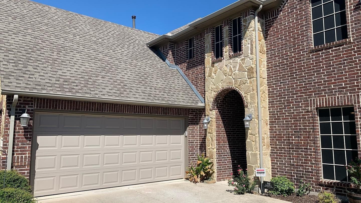 A large brick house with a garage door and a gray roof.