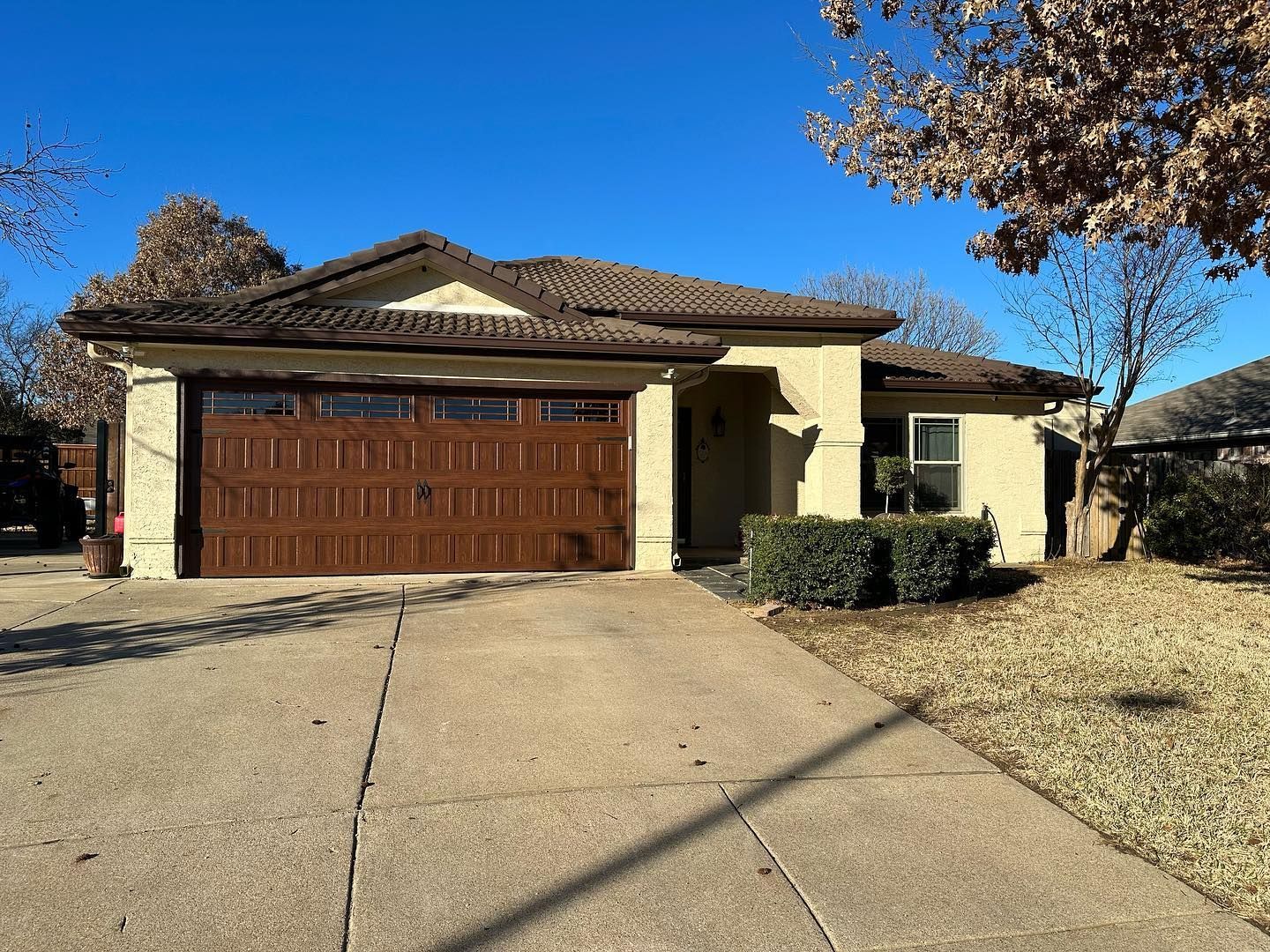 A house with a large garage door and a tree in front of it.