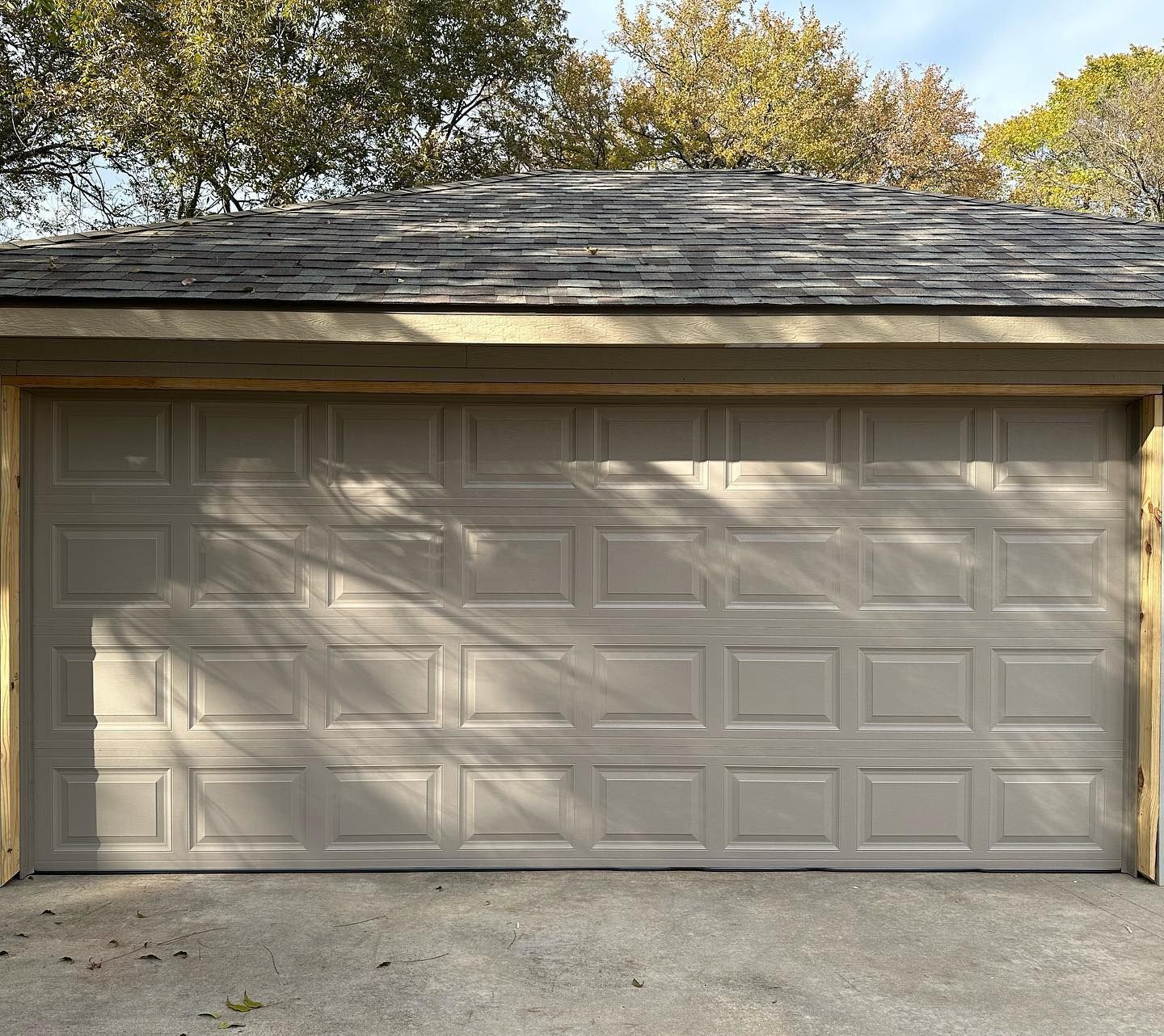 A garage door with a roof and trees in the background
