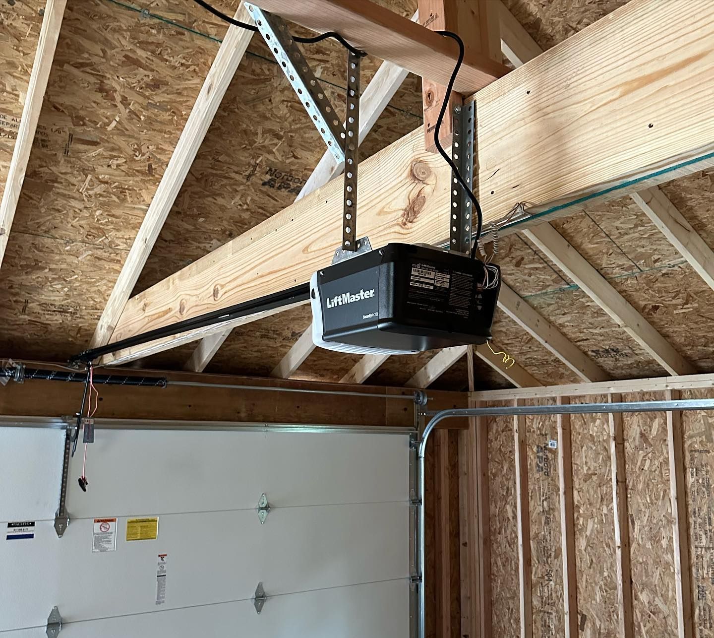 A garage door opener is hanging from the ceiling of a building.