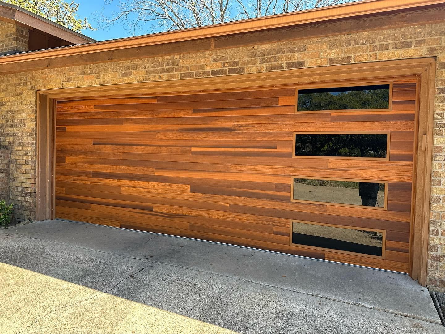 A wooden garage door with a brick building in the background.