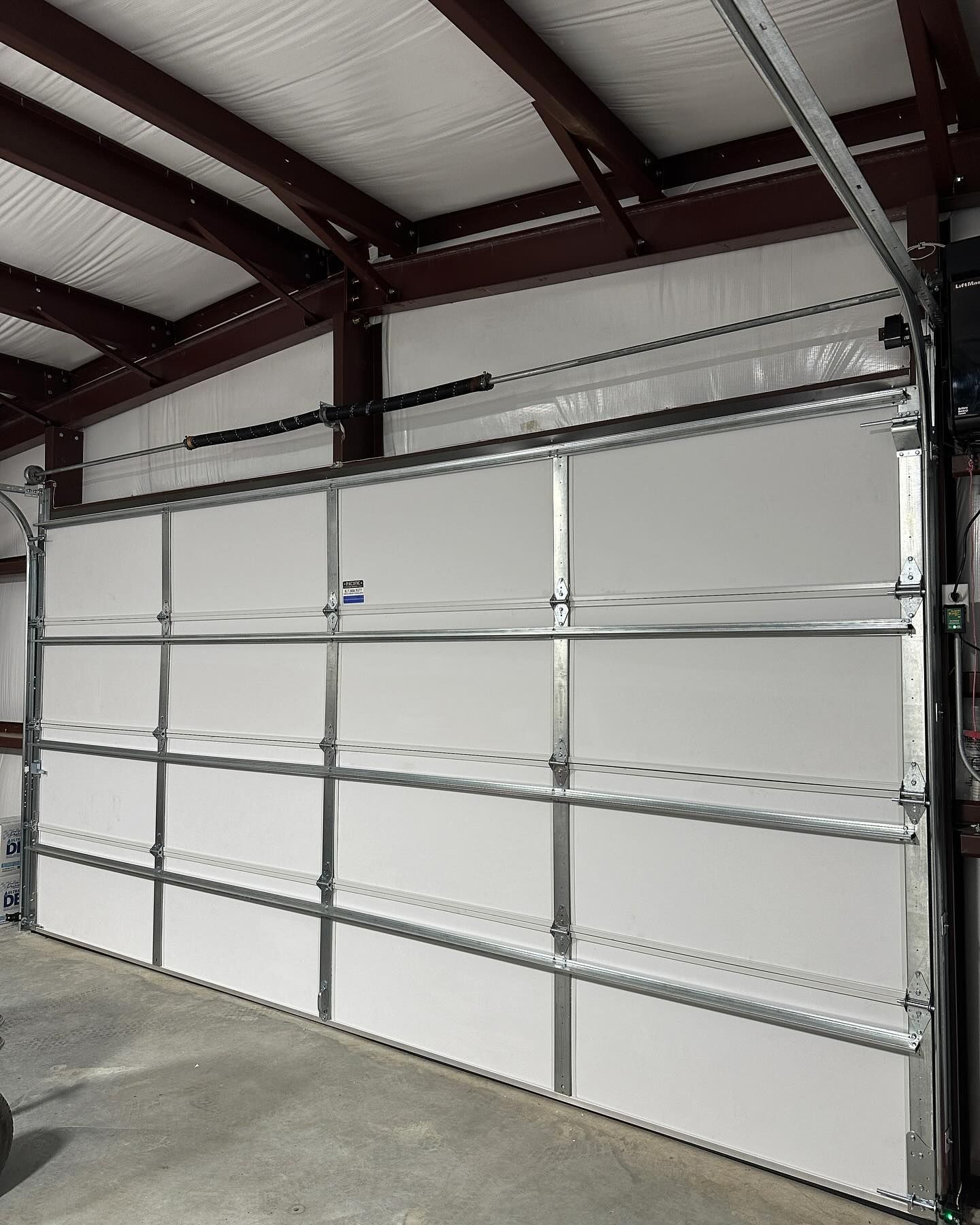 A large white garage door is open in a garage.