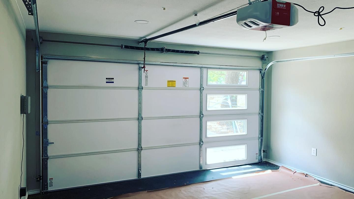 An empty garage with a garage door open and a garage door opener.