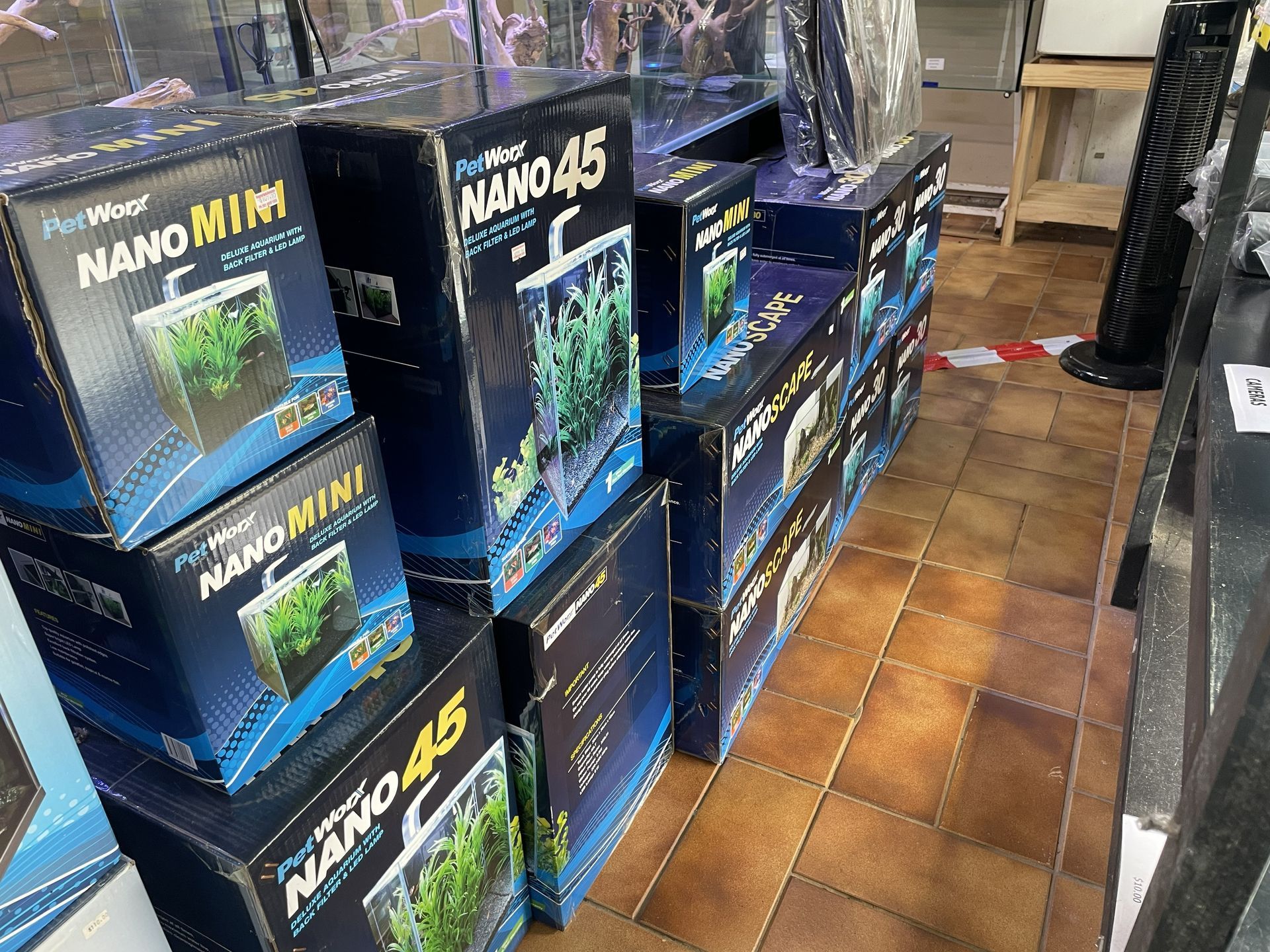 Boxes of aquarium kits stacked in a store. The boxes are blue and black, with product names visible.