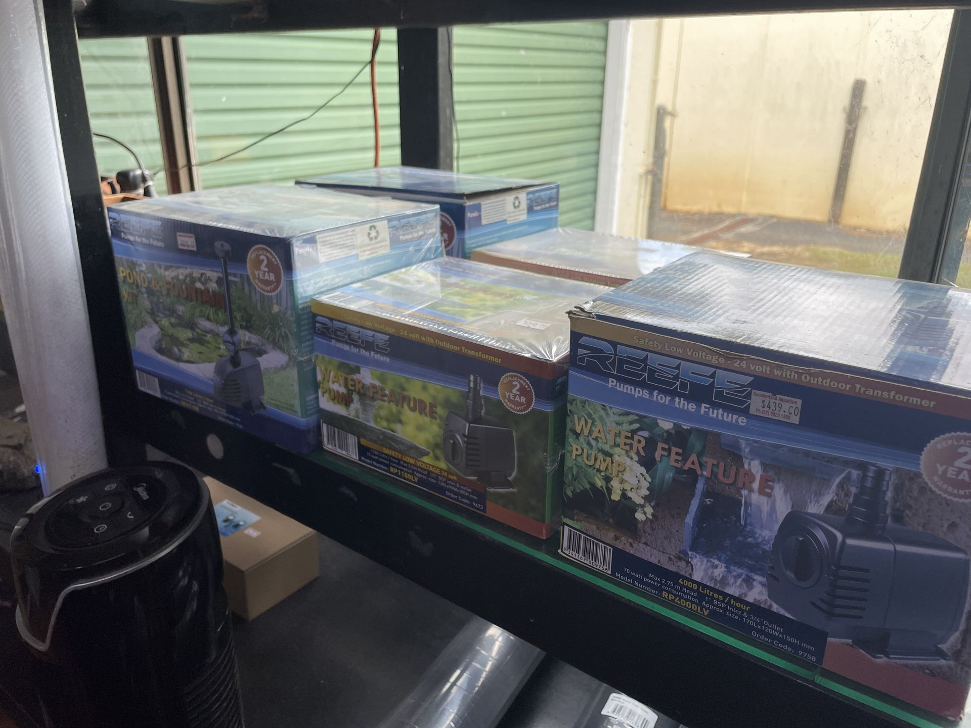 Boxes of aquarium equipment on a shelf in a store, with a window in the background.
