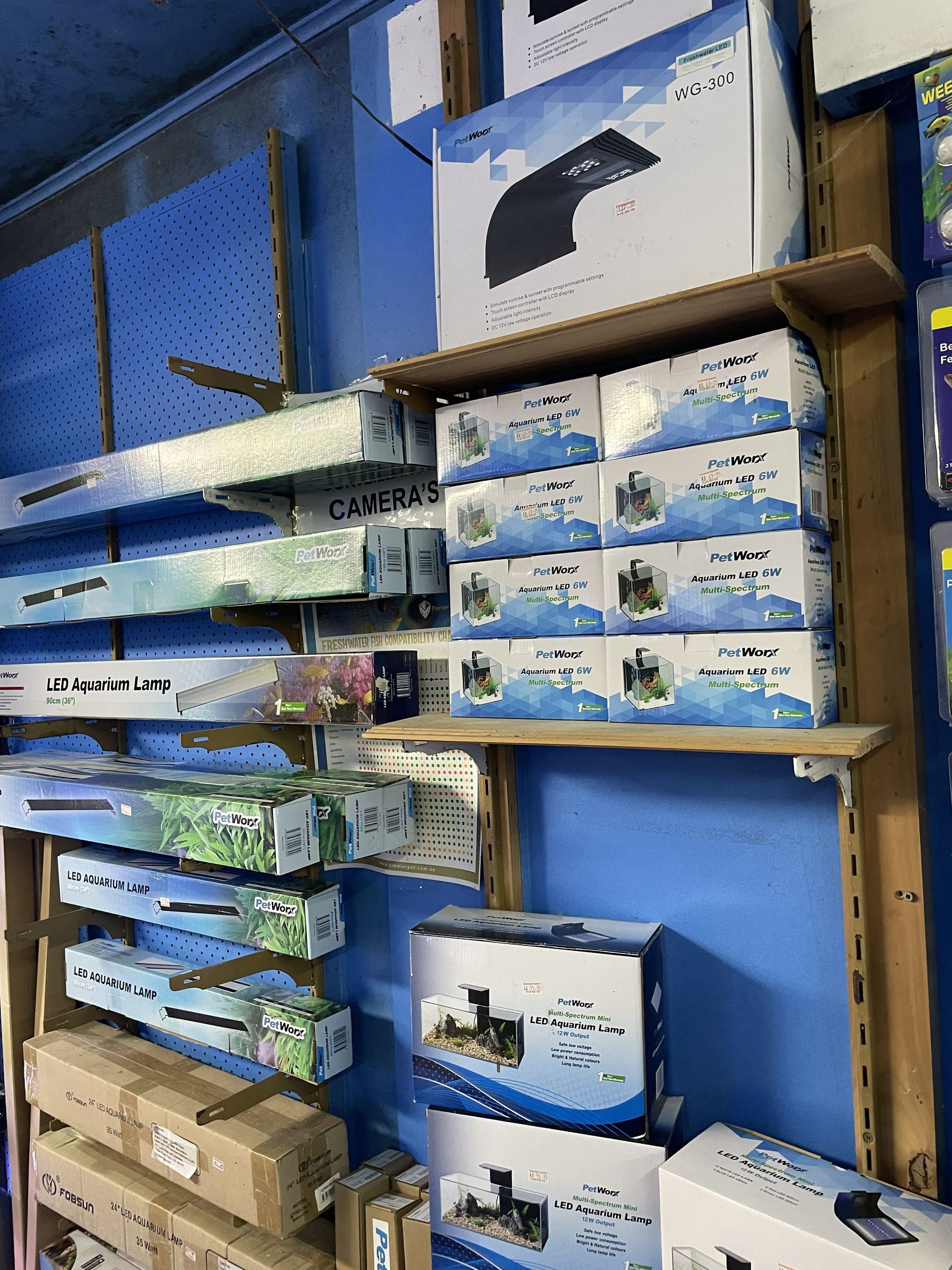 Shelves stocked with boxed aquarium equipment in a store, including lights and filters.