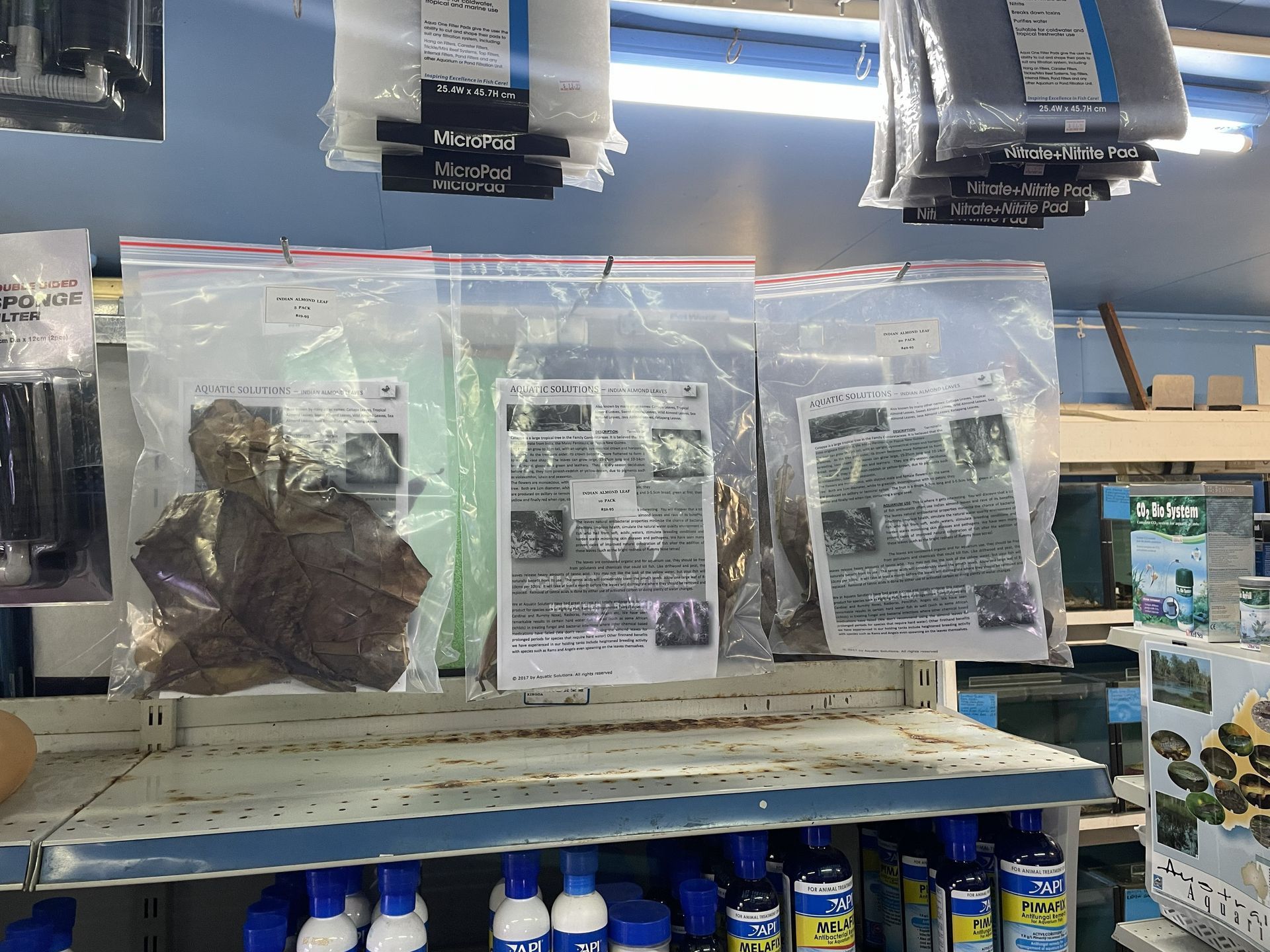 Bags of aquarium supplies hanging on a shelf, including rocks, plants, and care instructions.
