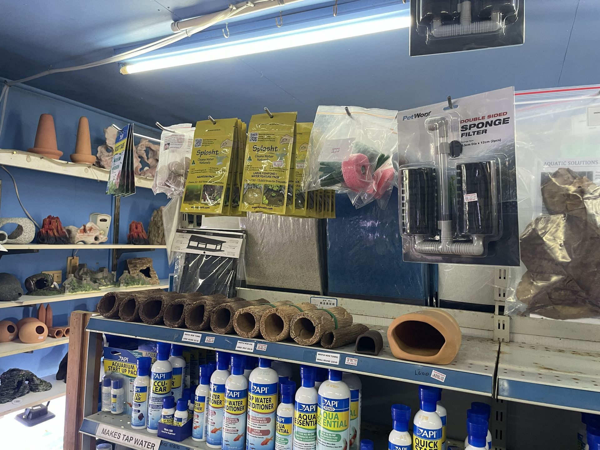 Shelves in a pet store stocked with aquarium supplies, including decorations, filters, and water treatments.