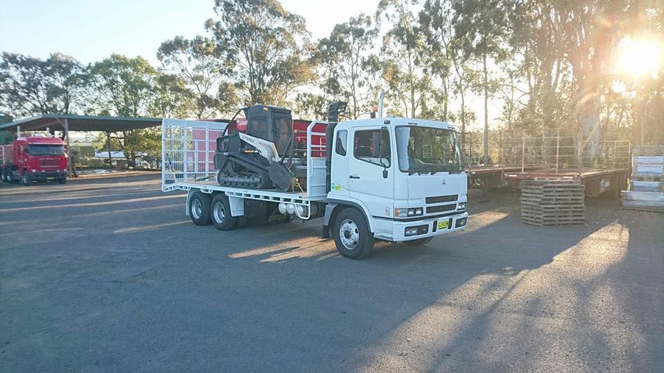 A white truck with a tractor on the back is parked in a parking lot.