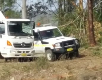 Two white trucks are parked next to each other in a field.