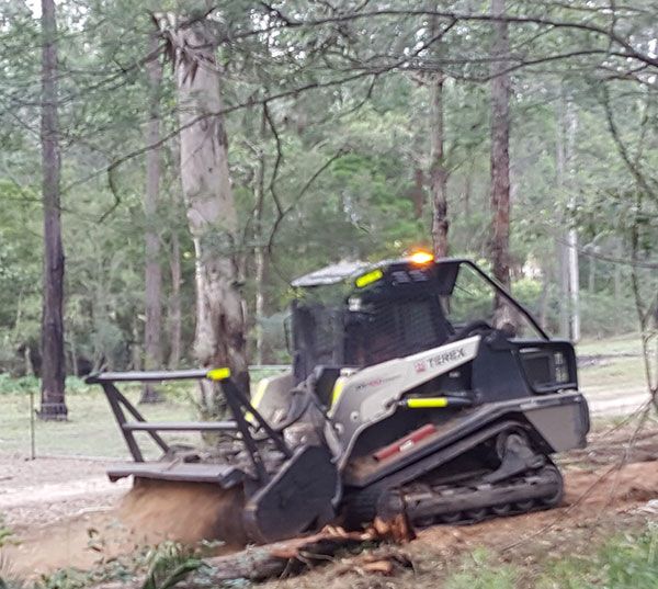 A bulldozer is cutting down trees in the woods.