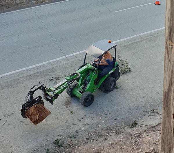 A man is driving a green tractor down a road