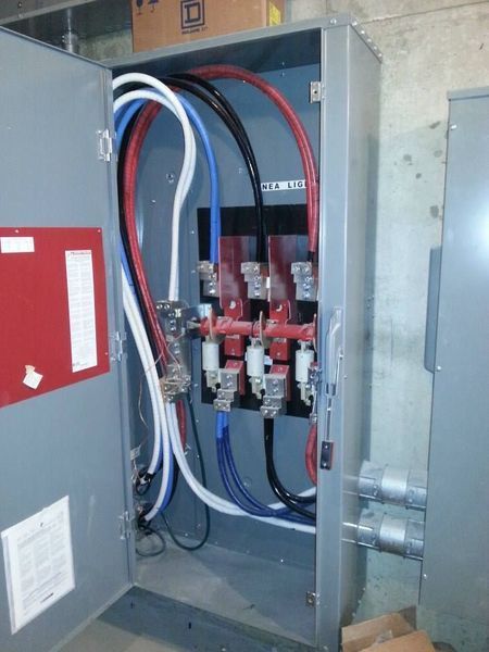 Electrical panel with red, blue, and black wires connected to breakers inside a gray metal box.