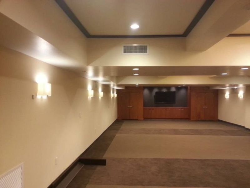 An empty, neutral-toned room with sconce lighting and a built-in media center.