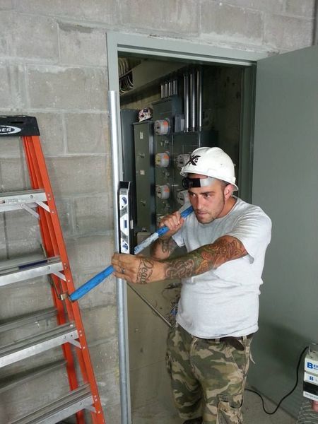 Construction worker in a white helmet uses a level on a door frame in a concrete room.