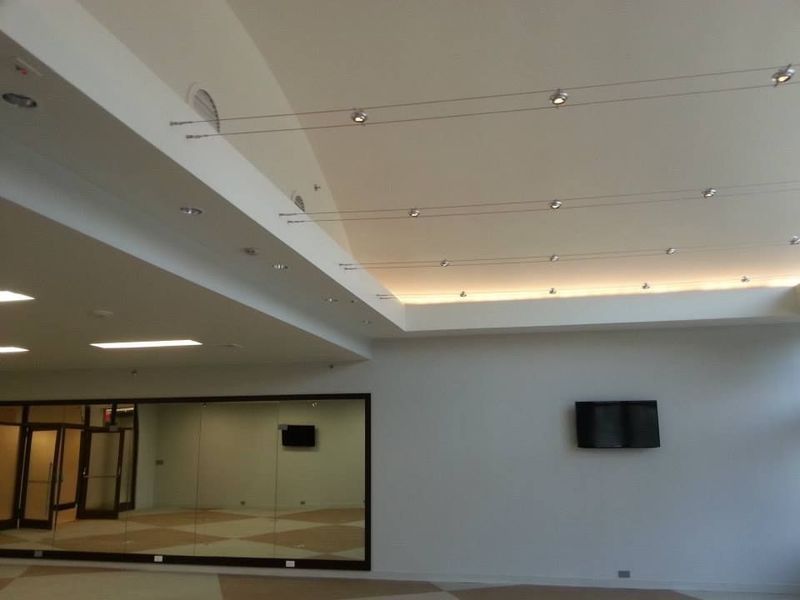 Bright white room with a large mirror, two rows of lights, and a television.