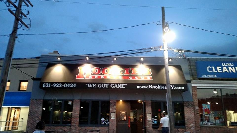 Hook & Vine restaurant storefront with lit sign at dusk. Text on building says