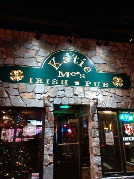 Katie Mc's Irish Pub entrance sign; green and gold on a stone wall.