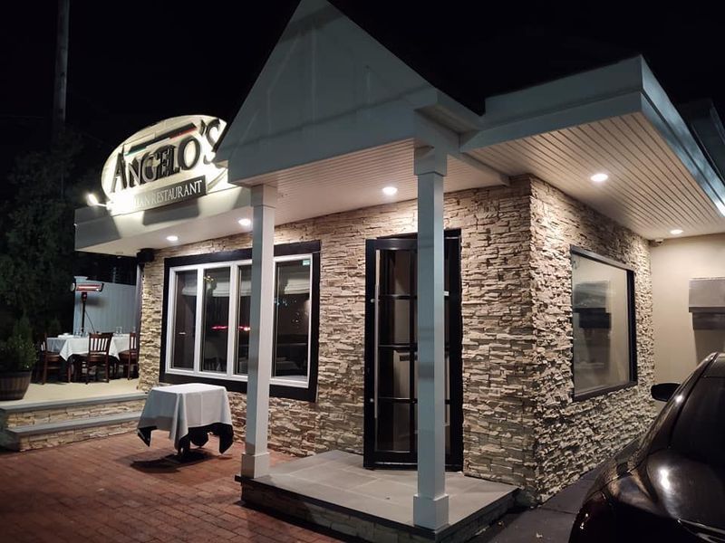 Angelo's Restaurant exterior at night, with a stone facade, lit sign, windows, and a covered entryway.