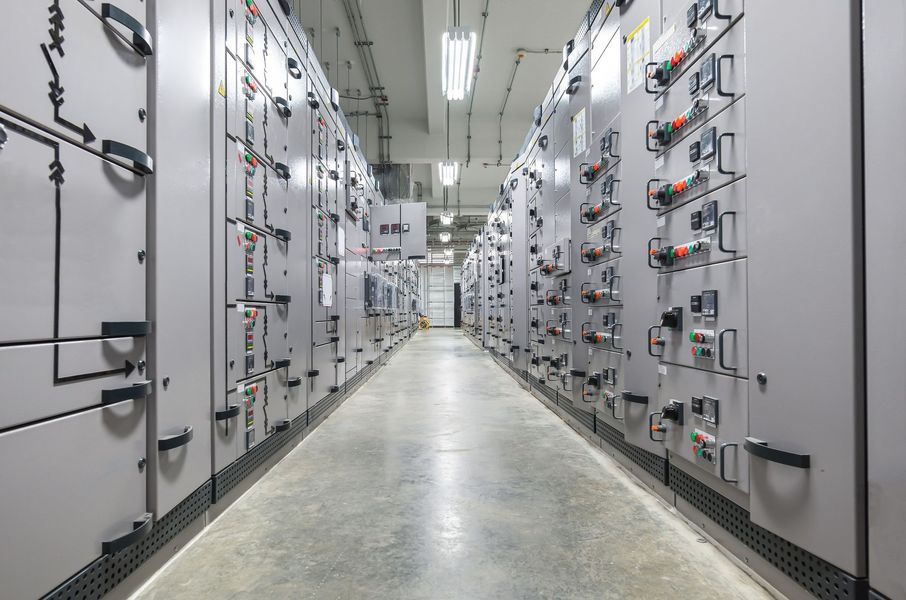 Hallway with gray electrical panels and fluorescent lights.