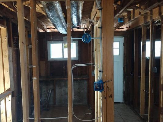 Framing of a room during construction with electrical wiring and a doorway.