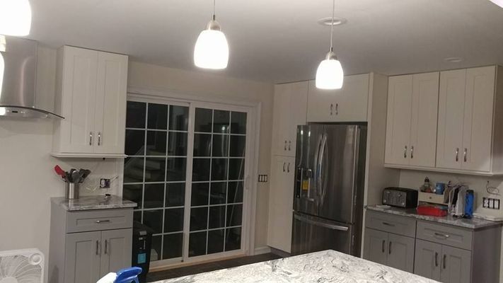 A modern kitchen with white and gray cabinets, stainless steel appliances, and a sliding glass door.