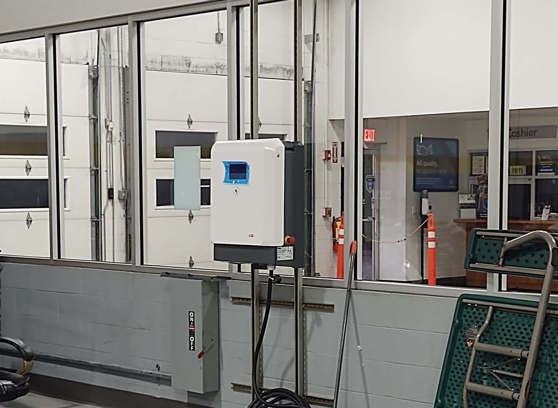 White solar inverter unit mounted on a wall inside a commercial building, with garage doors in the background.