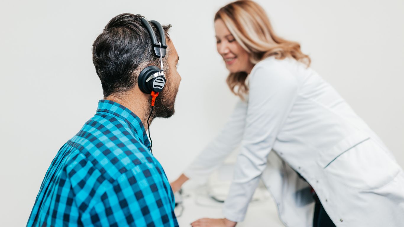 A professional wearing a lab coat conducts a hearing test for a patient wearing headphones in a clinic.