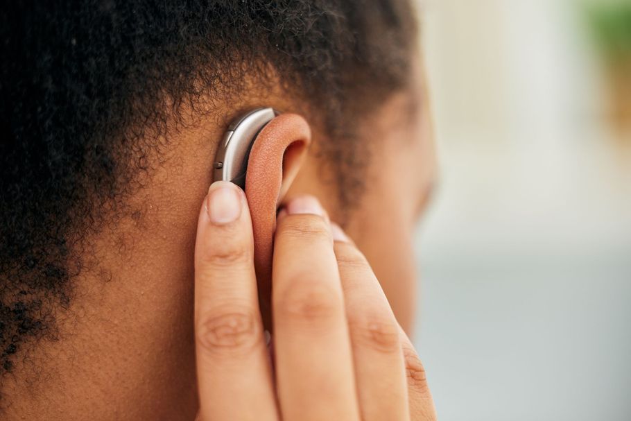 A close-up view of a beige behind-the-ear hearing aid worn by an individual.
