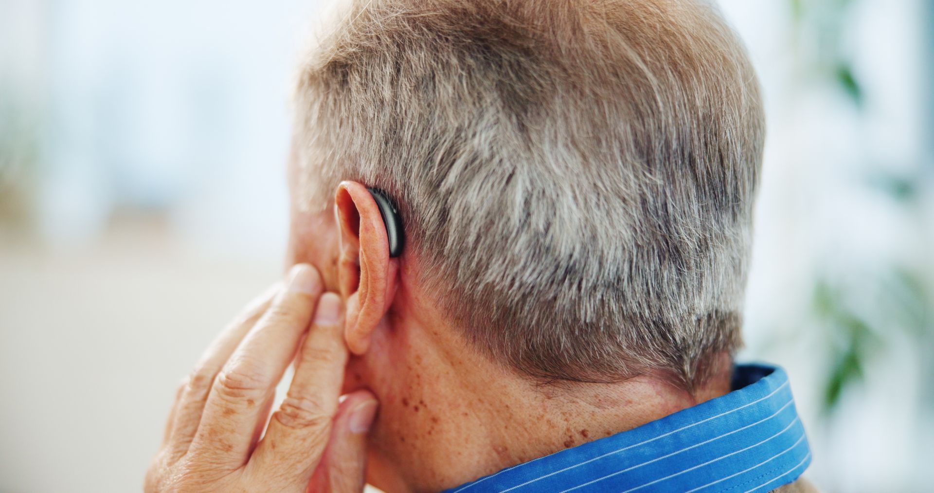 A close-up view of a beige behind-the-ear hearing aid worn by an individual.