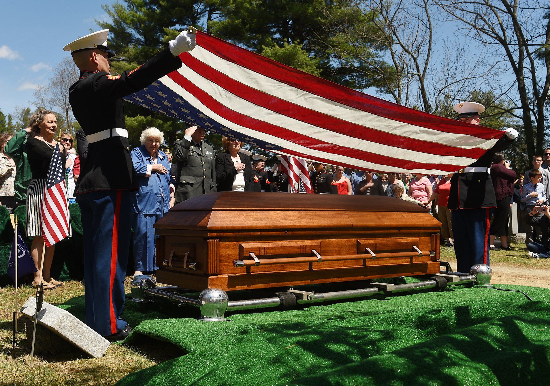 A coffin is being draped with an american flag