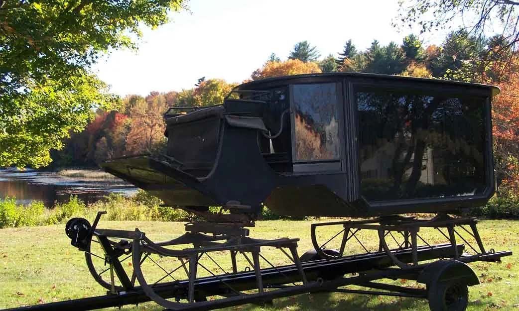 A black vehicle is parked on a trailer in a field