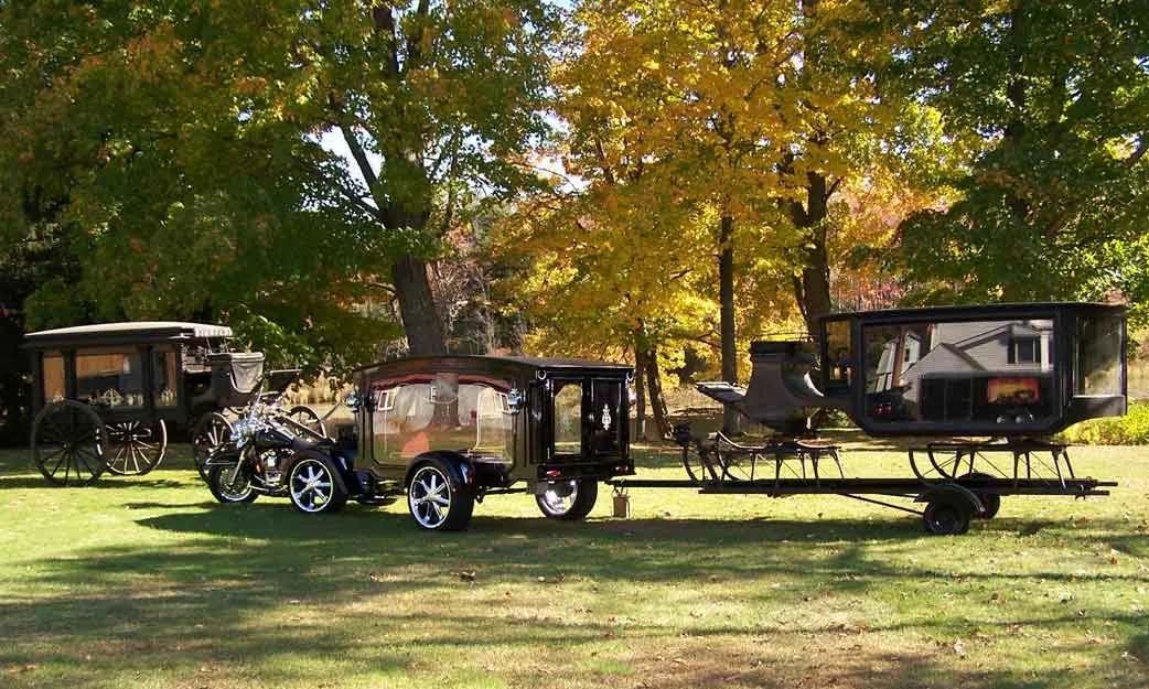 Two horse drawn carriages are parked in a grassy field.