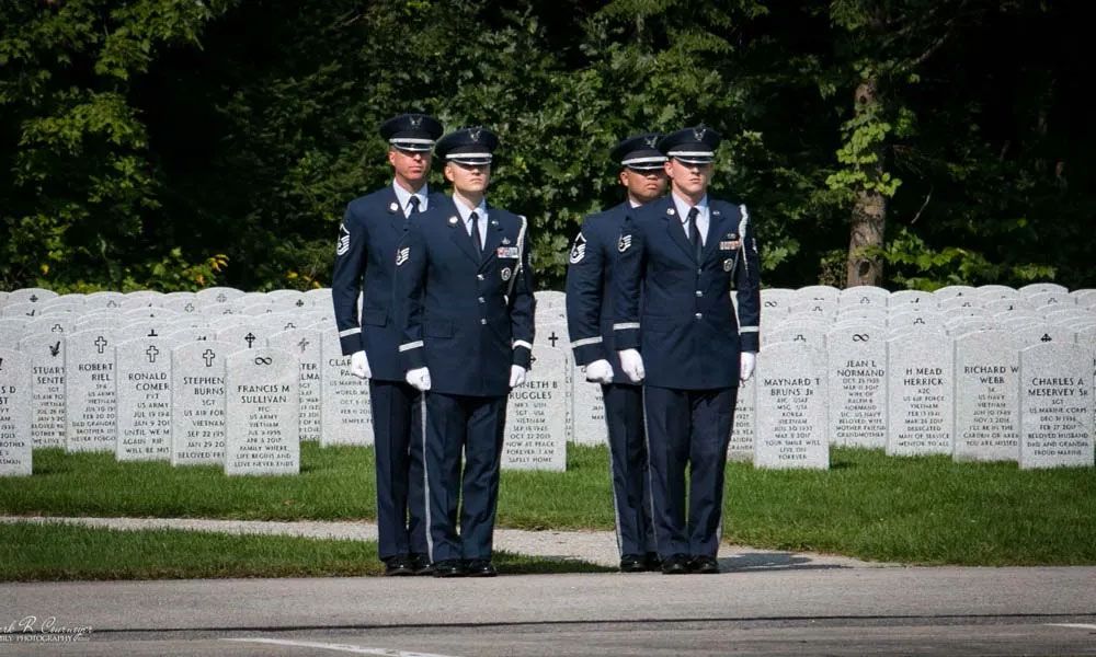 A group of soldiers are standing in front of a cemetery.