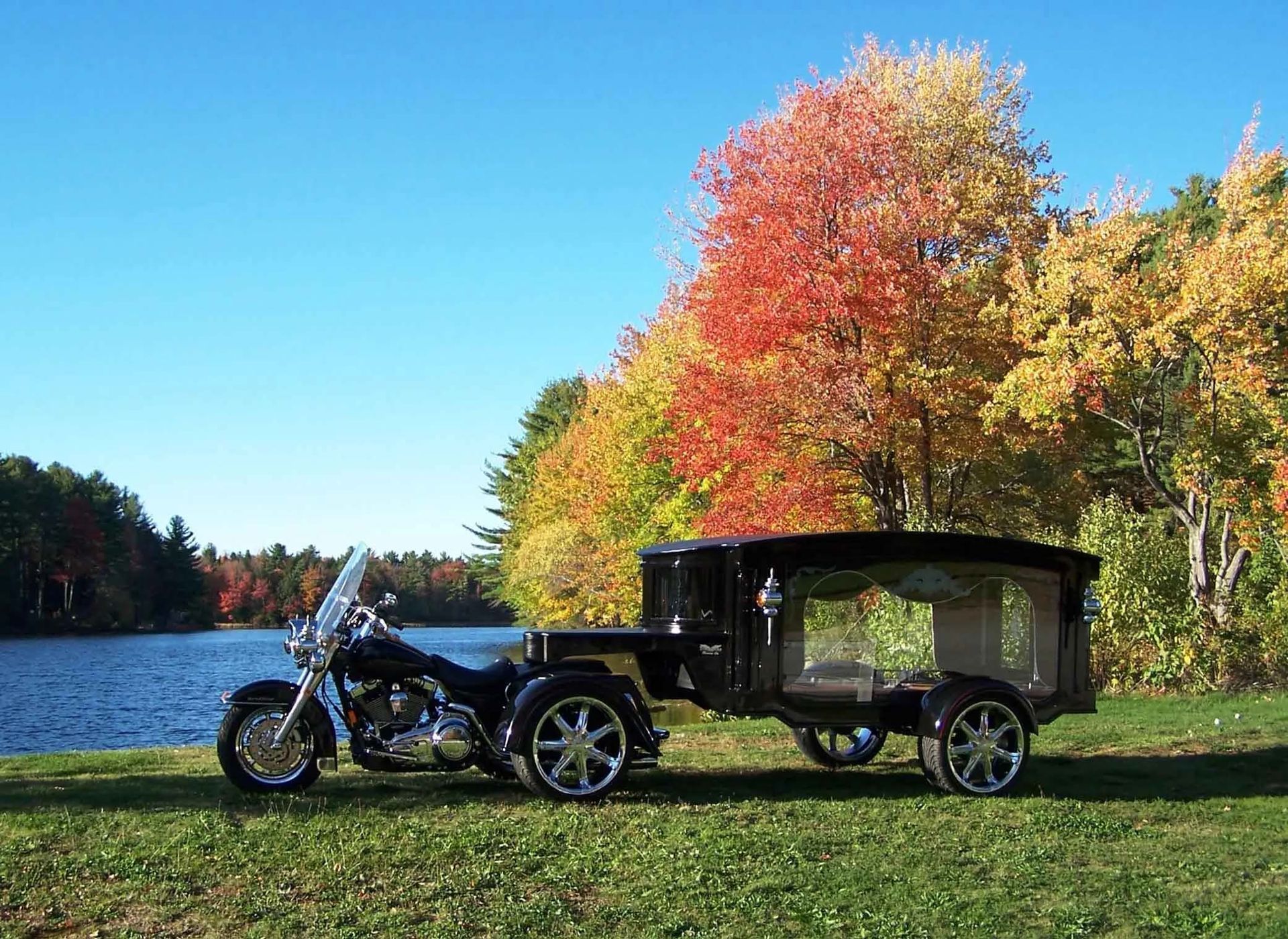 A motorcycle with a trailer attached to it is parked next to a body of water.