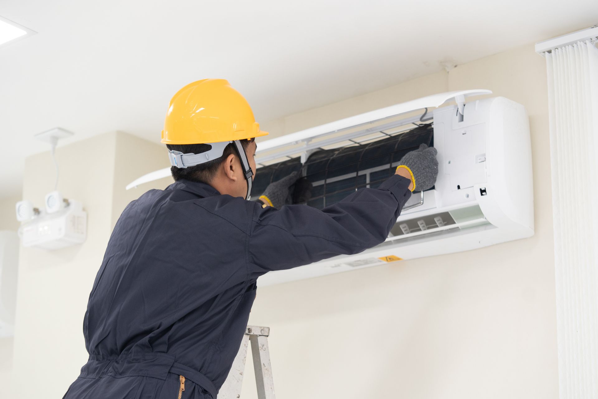 A man is fixing an air conditioner with a screwdriver. A man is fixing an air conditioner with a screwdriver.