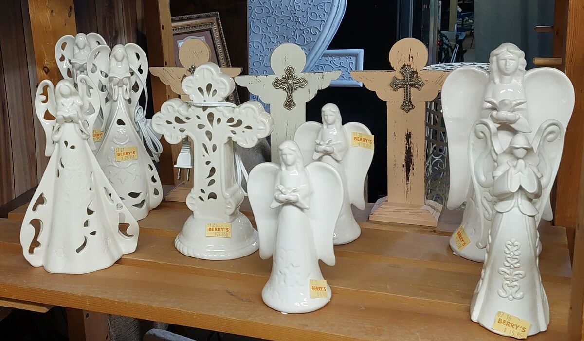 A group of white angels and crosses are sitting on a wooden shelf.
