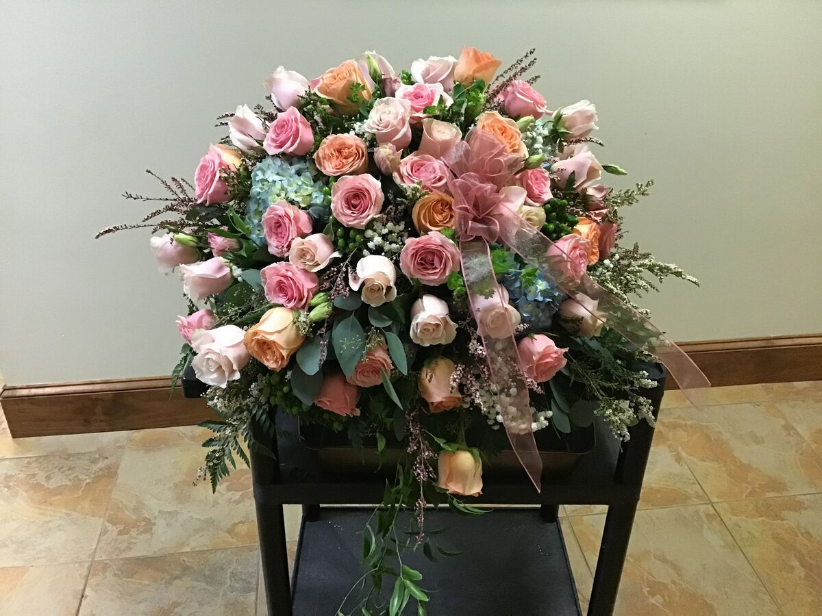 A large bouquet of pink roses is sitting on top of a piano stool.