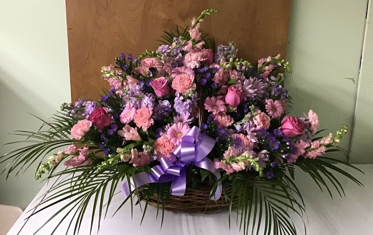 A basket filled with pink and purple flowers is sitting on a table.